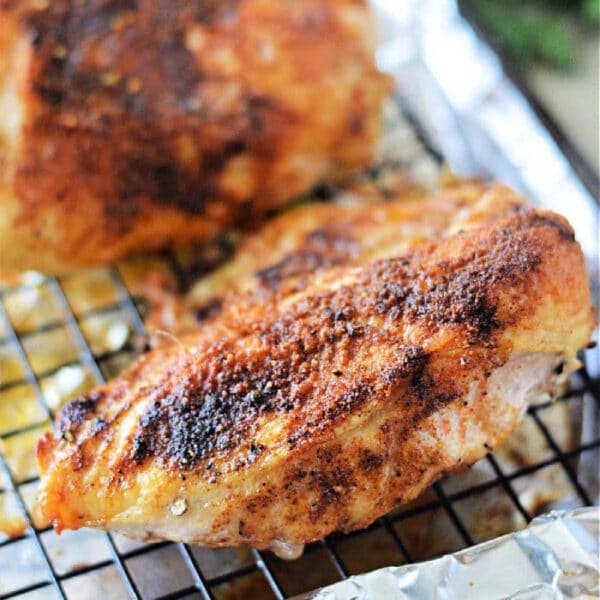 Seasoned and cooked chicken breast rests on a wire rack over foil, ready to serve—showcasing perfection after finding out just how long to cook chicken breast in oven 350 for juicy results.