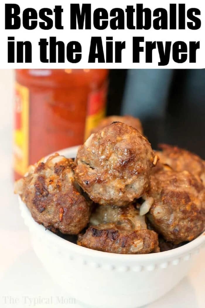 A white bowl filled with meatballs in air fryer sits in front of a jar of red sauce.