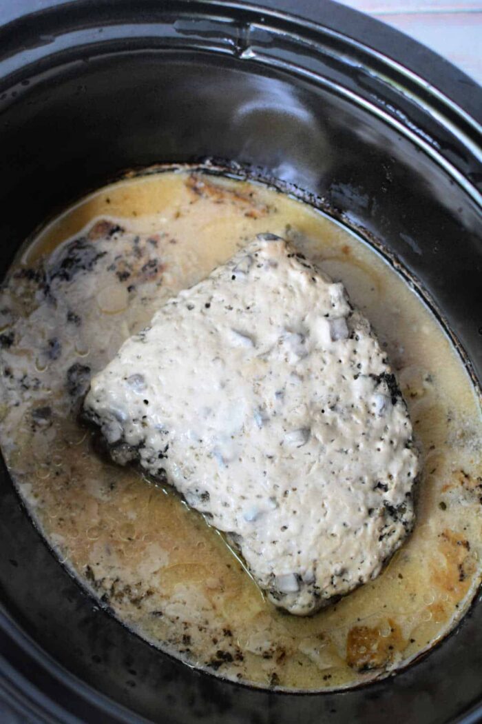 London Broil for the Slow Cooker simmers in a creamy sauce, filling the black slow cooker with savory aromas as the meat becomes tender and flavorful.