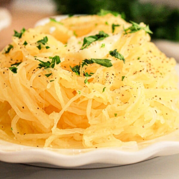 A slow cooker spaghetti squash sits on the plate, enhanced by a parsley garnish and a sprinkle of black pepper.