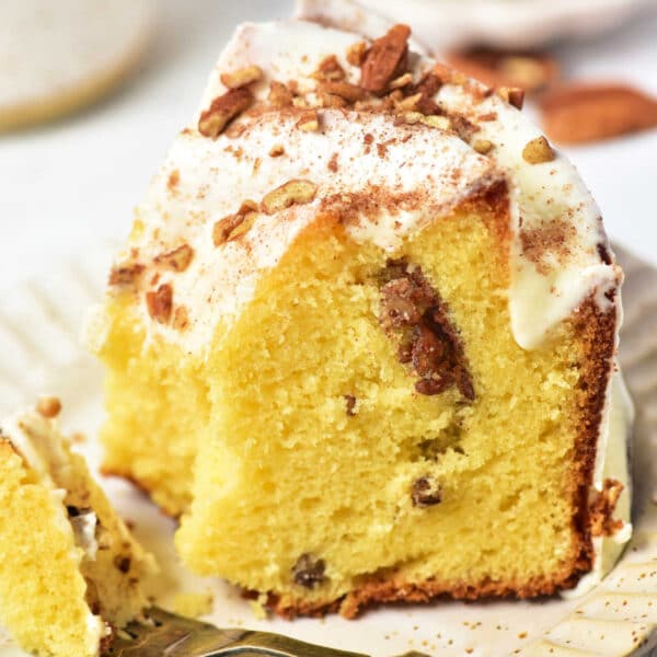 A slice of Sock it to me cake, made with a delightful cake mix, sits on a plate with frosting and nuts, accompanied by a fork.