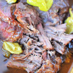 Close-up of juicy, shredded beef with peppers in rich broth, reminiscent of a savory Mississippi Pot Roast.