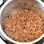 Instant Pot frozen ground beef browning perfectly, with dry pasta and a sauce jar ready on the counter for a quick and easy meal.