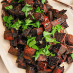 Cubed vibrant purple sweet potatoes sit elegantly on a white plate, complemented by a handy spoon.