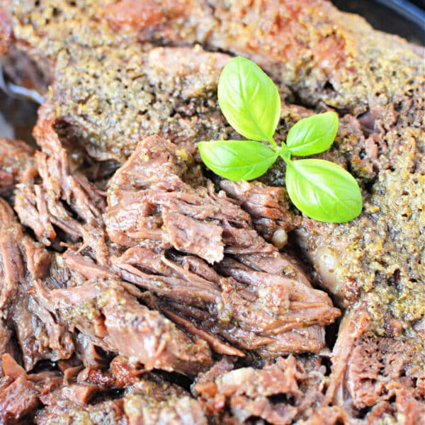A close-up of perfectly cooked boneless beef topped with fresh green basil leaves.