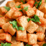 A pile of crispy roasted white sweet potato cubes garnished with fresh parsley.