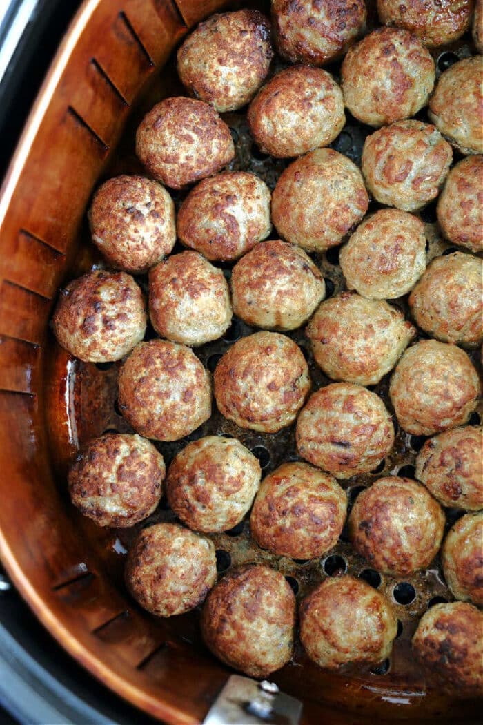 Golden brown, crispy frozen meatballs in air fryer basket, perfectly cooked and ready to enjoy.