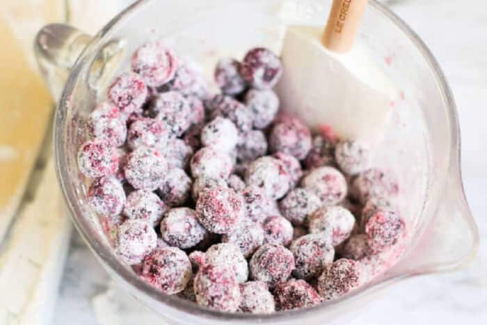 Glass bowl of fresh cranberries coated in sugar, with a white spatula inside the bowl&mdash;perfect for adding a sweet-tart twist to your next strudel pastry.