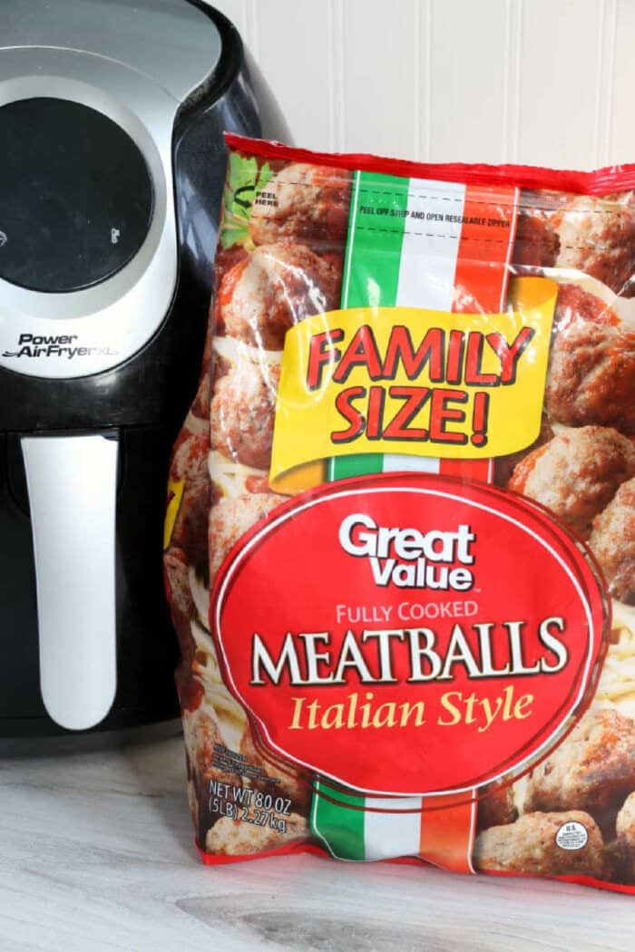 A bag of Great Value Italian Style Meatballs sits next to a black and silver air fryer, ready for a quick meal of frozen meatballs in air fryer perfection.