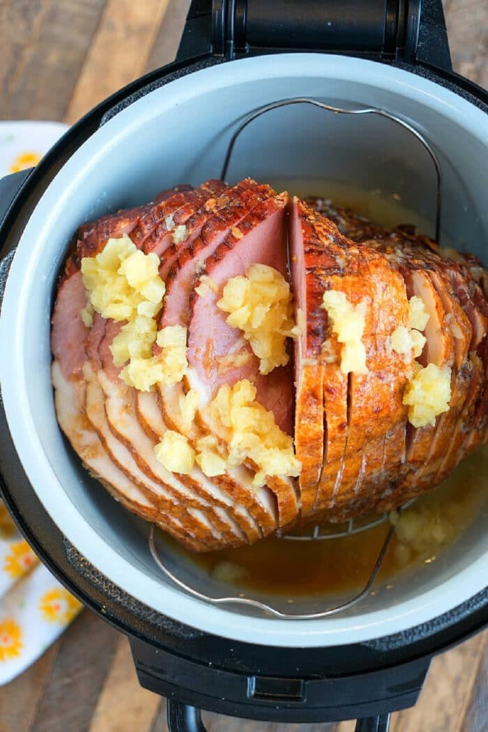 A spiral-cut ham with pineapple chunks and juice in a Ninja Foodi, ready to be cooked to perfection.