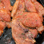Seared flavorful Pork Shoulder Steak, coated with seasoning and sizzling in a cast iron skillet.