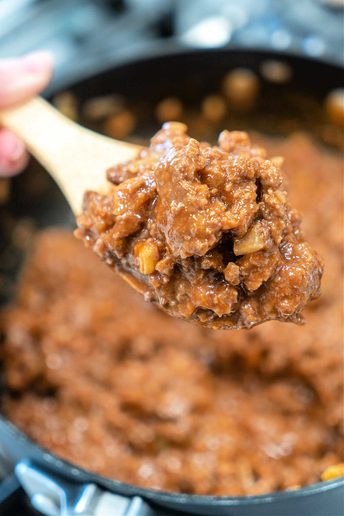 A wooden spoon holds a scoop of thick, chunky beef stew above a pot of the same stew&mdash;comfort food that&rsquo;s almost as simple as an easy sloppy joe recipe with 3 ingredients.