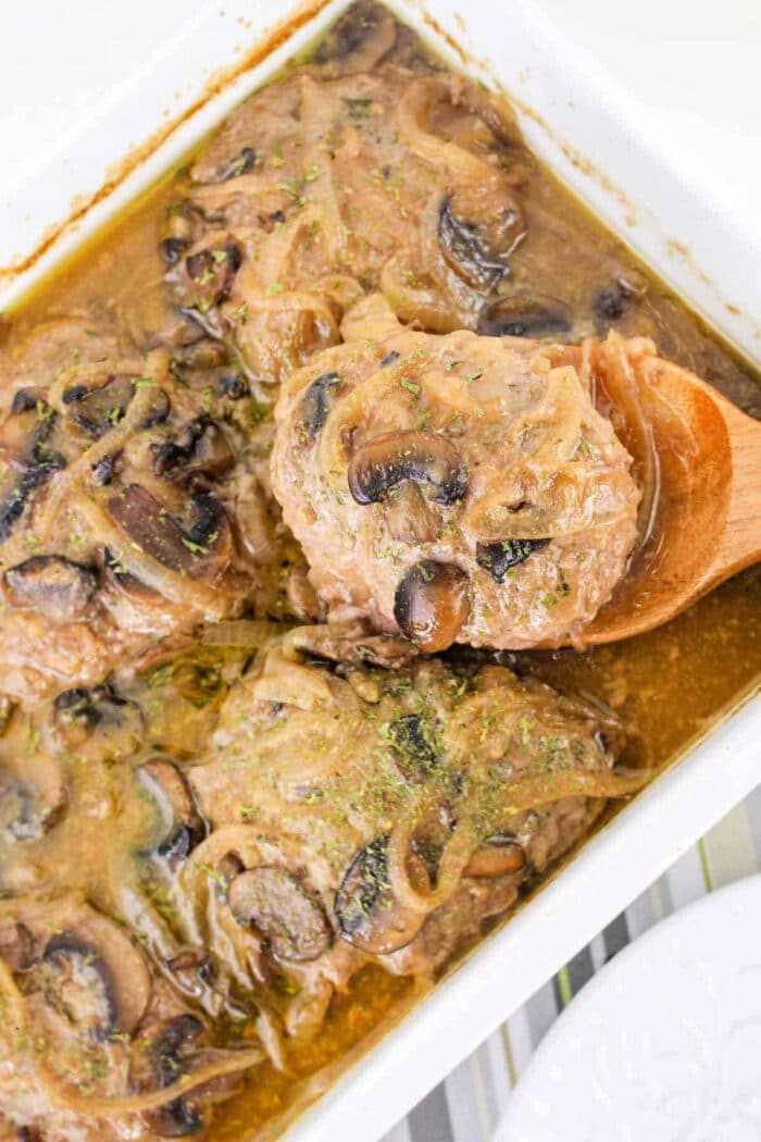 Baked chicken breasts with mushrooms and onions in a savory brown sauce, reminiscent of classic Hamburger Steak, served in a white casserole dish.