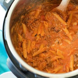 Pasta with meat sauce being stirred with a wooden spoon inside an Instant Pot for a delicious pressure cooker lasagna casserole.