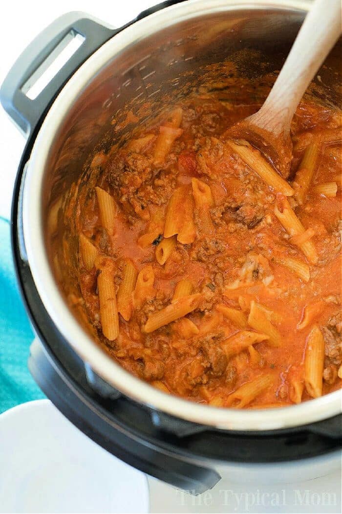 Pasta with meat sauce being stirred with a wooden spoon inside an Instant Pot for a delicious pressure cooker lasagna casserole.
