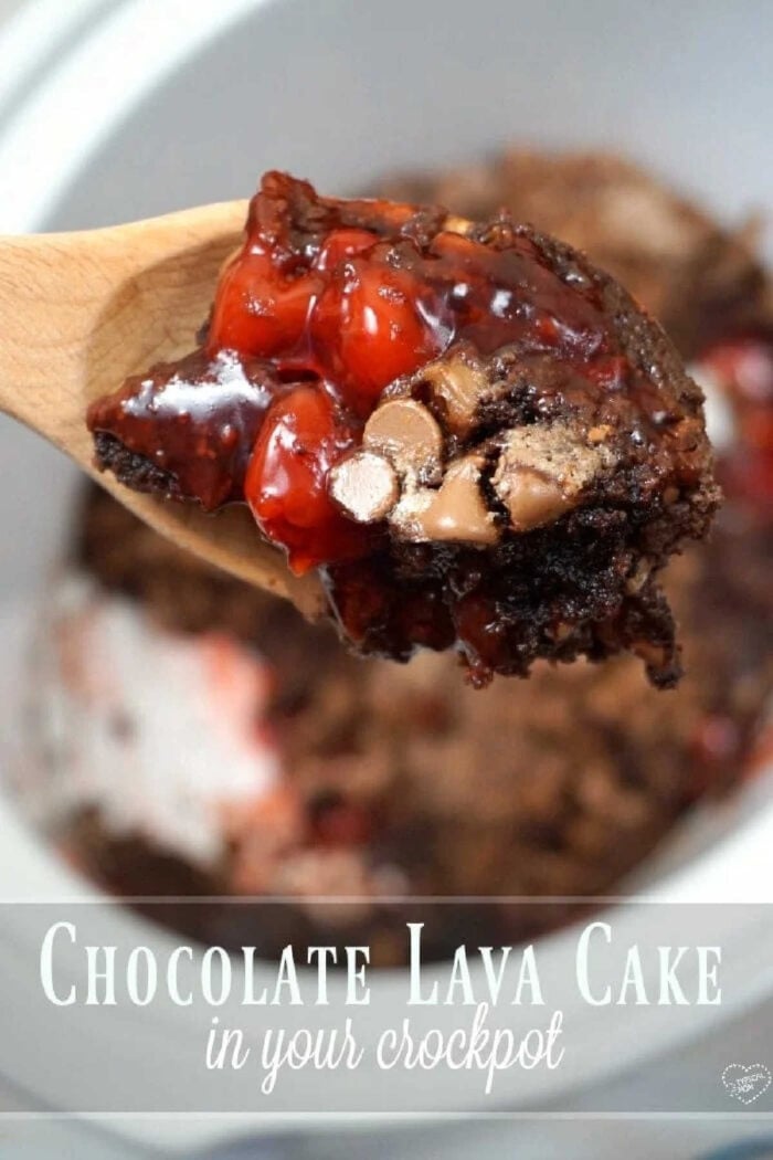 A wooden spoon holds gooey crockpot lava cake with cake mix, cherries, and chocolate chips over a bubbling slow cooker.