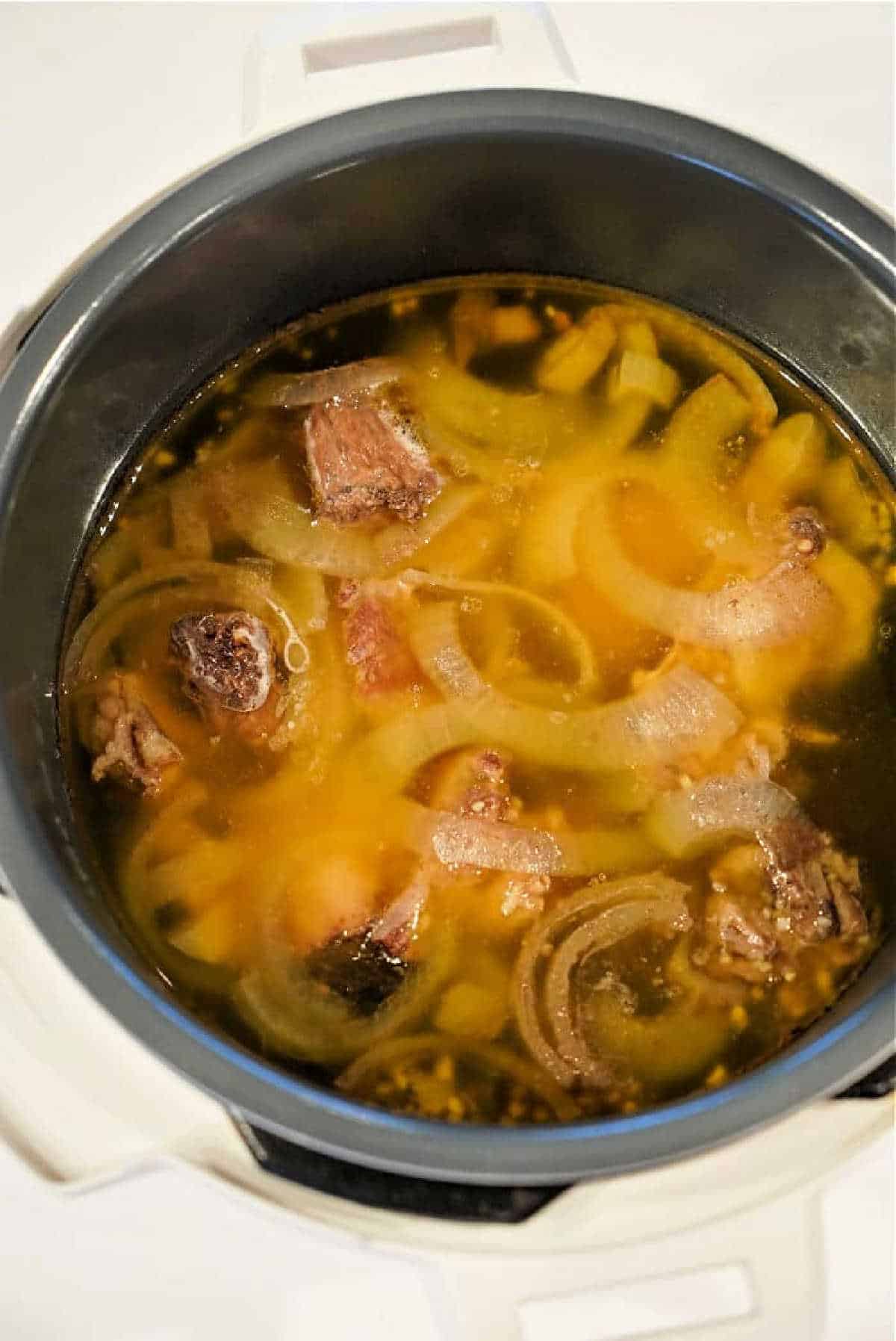 A pot of soup with meat chunks and sliced onions in a rich bone broth, perfect for trying your favorite Bone Broth Recipe Instant Pot style.