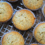 Freshly baked banana muffins in paper liners cooling on a wire rack—perfect for trying out your favorite banana muffin recipe.