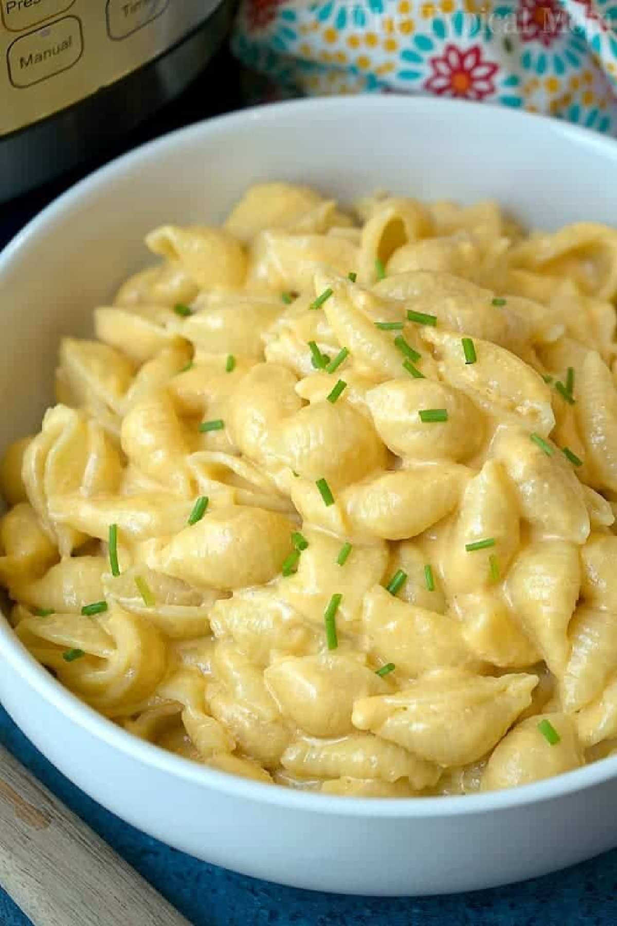 A bowl of creamy instant pot macaroni and cheese shells topped with chopped chives.