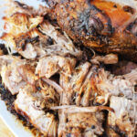 Shredded, seasoned pork roast with crispy, browned edges on a white plate—an irresistible pork roast recipe made to perfection in the oven.