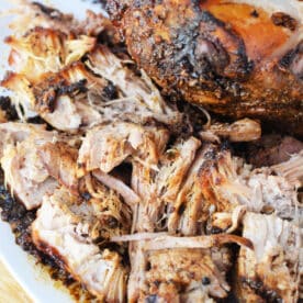 Shredded, seasoned pork roast with crispy, browned edges on a white plate—an irresistible pork roast recipe made to perfection in the oven.