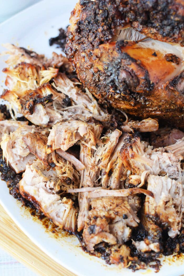Shredded, seasoned pork roast with crispy, browned edges on a white plate—an irresistible pork roast recipe made to perfection in the oven.
