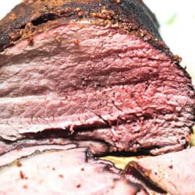 Sliced Smoked Sirloin Tip Roast displays a juicy interior and a dark, seasoned crust, just like classic smoked beef brisket.