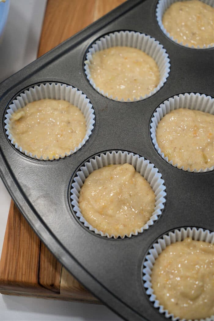Banana muffin batter in paper liners inside a muffin tin, ready to be baked—perfect for trying out your favorite Banana Muffin Recipe.