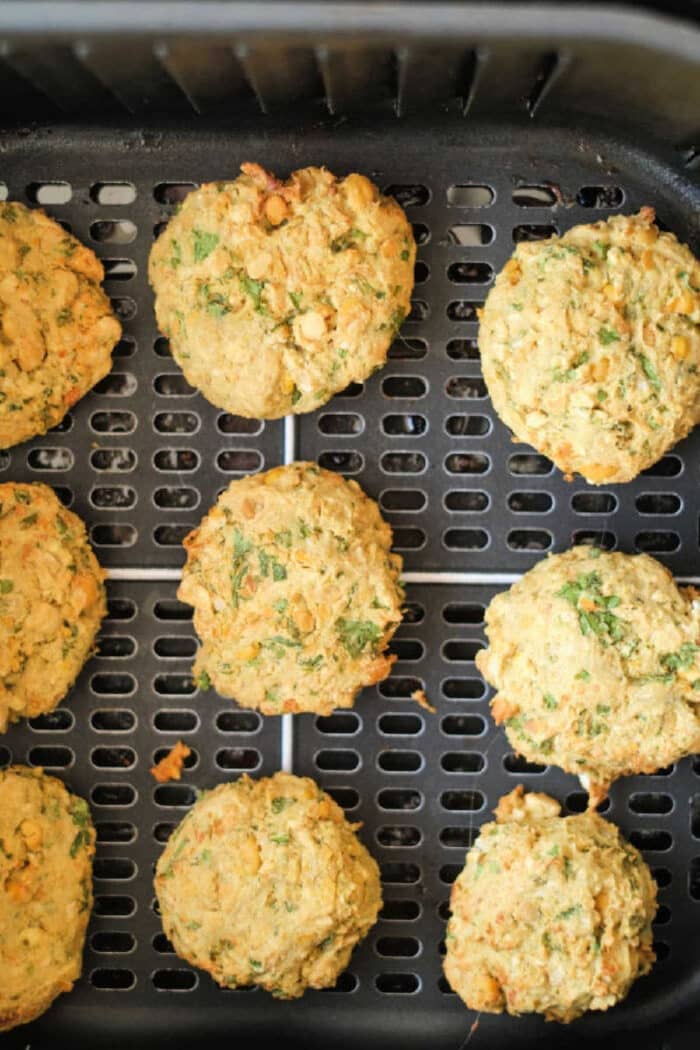 Nine air fryer falafel patties on a tray, golden brown and flecked with herbs.