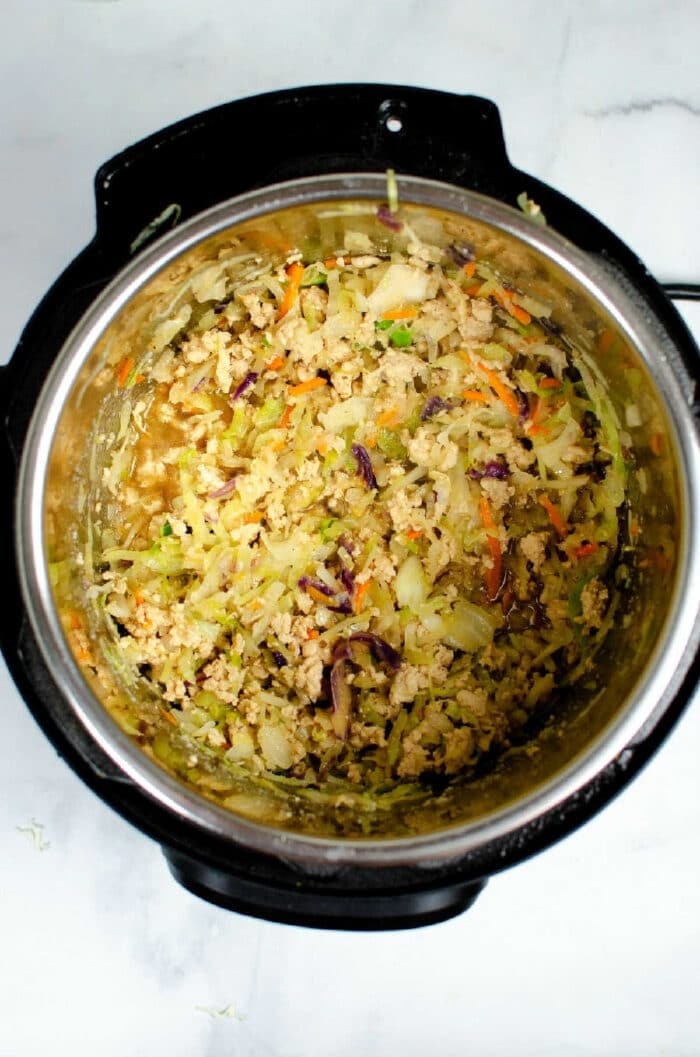 Shredded vegetables and rice mixture for instant pot Egg Roll in a Bowl inside an Instant Pot on a white surface.