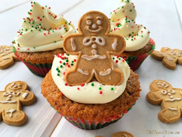 Cupcakes with white frosting, colorful sprinkles, and gingerbread man cookies on top, surrounded by more cookies—perfect alongside a slice of Starbucks gingerbread loaf.