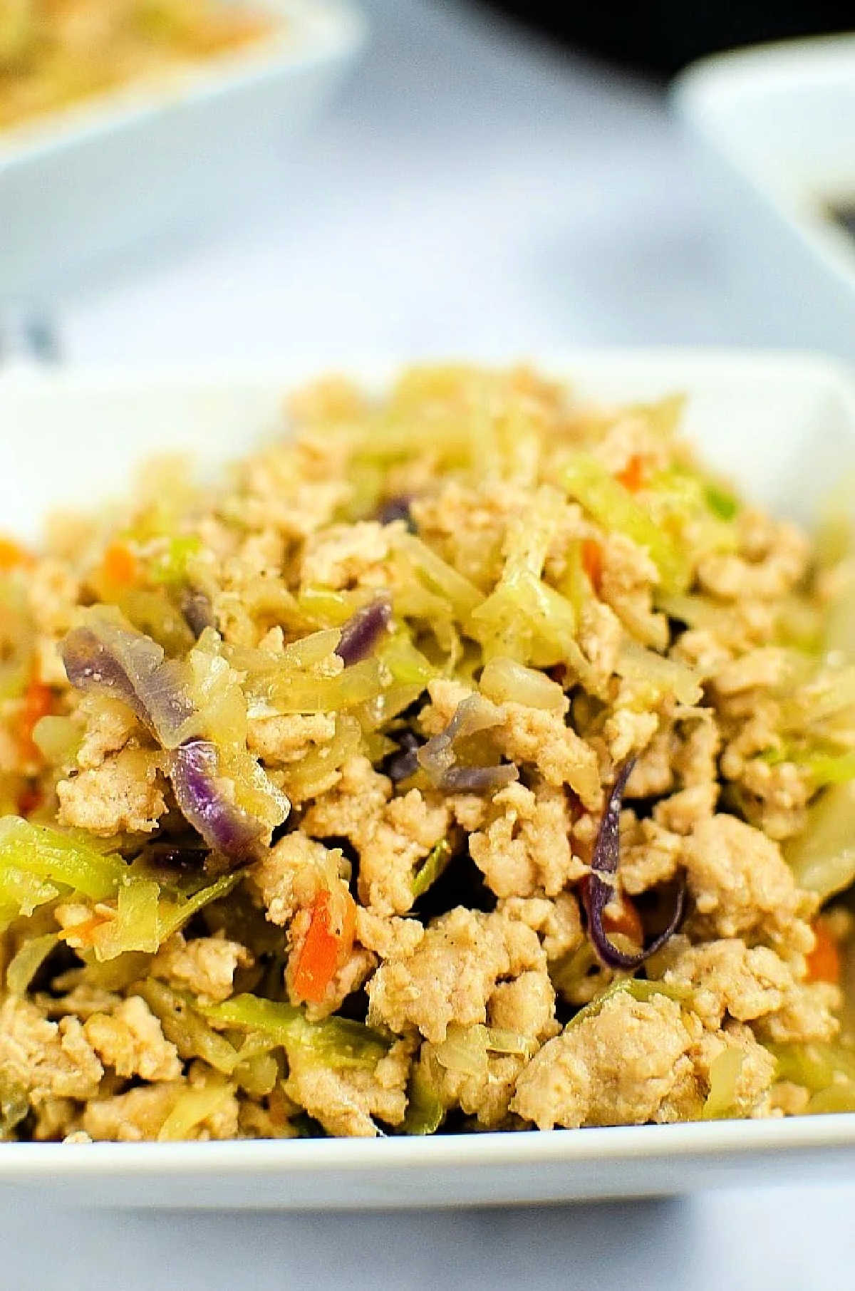 Instant Pot Egg Roll in a Bowl: Ground chicken stir-fry with shredded cabbage, carrots, and red cabbage, all served in a white bowl.