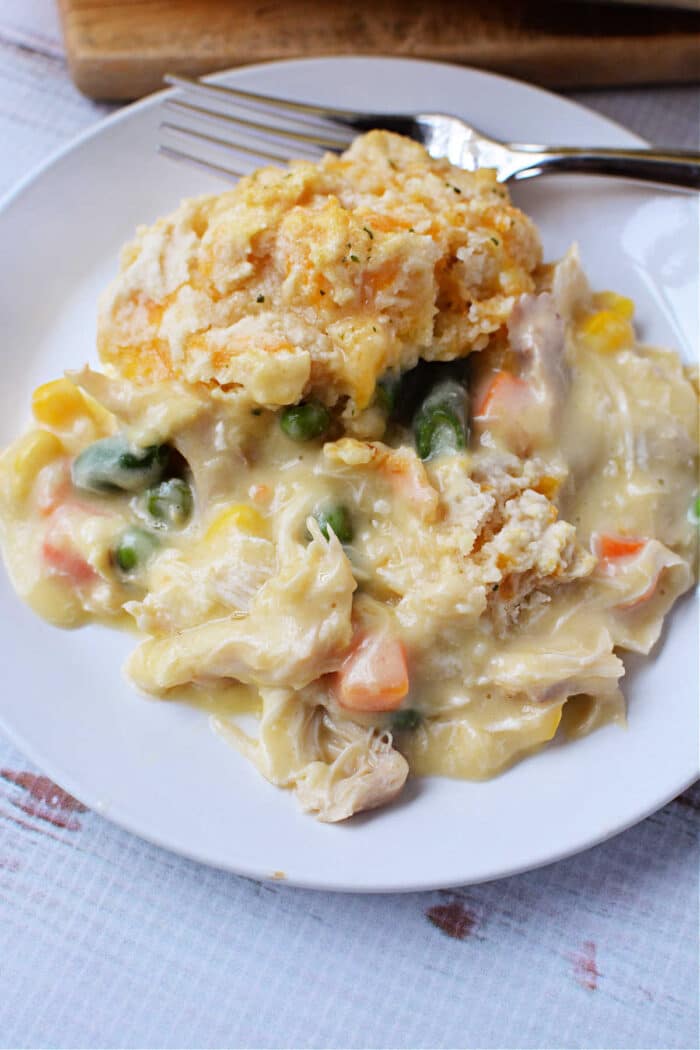 A plate of creamy chicken and vegetable casserole, reminiscent of Chicken Pot Pie, topped with a flaky Red Lobster Biscuit, with a fork on the side.