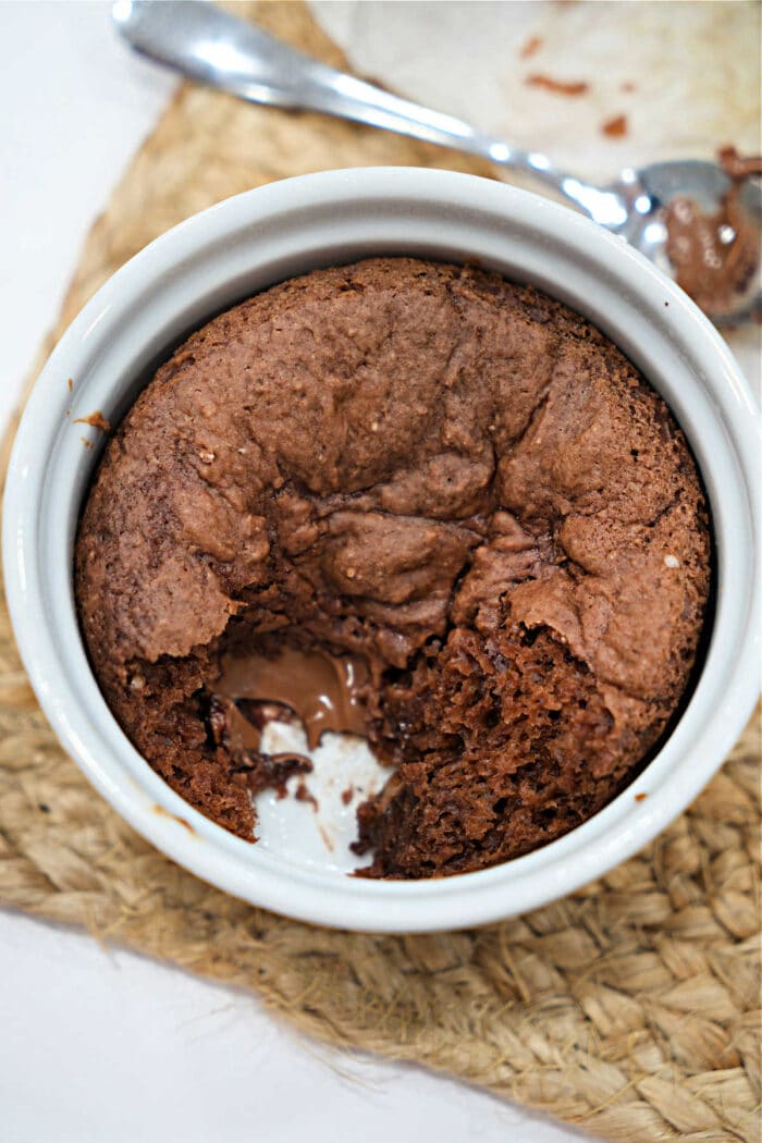 Chocolate lava cake in a white ramekin with a spoonful missing, revealing gooey melted chocolate inside—perfect for those who love the rich, decadent flavor of homemade treats like Chocolate Banana Bread.