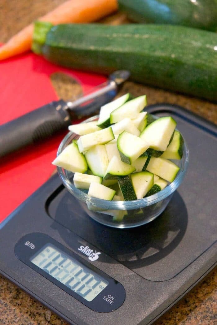 Easy Instant Pot minestrone soup recipe is full of flavor! Healthy and vegetarian too, my kids raved that this was their favorite pressure cooker soup. #instantpotrecipes #instantpot #pressurecooker #minestronesoup #vegetablesoup #soup #vegetarain #healthy #ninjafoodi #thetypicalmom A bowl of chopped zucchini on a scale, ready to be added to an easy Instant Pot minestrone soup.