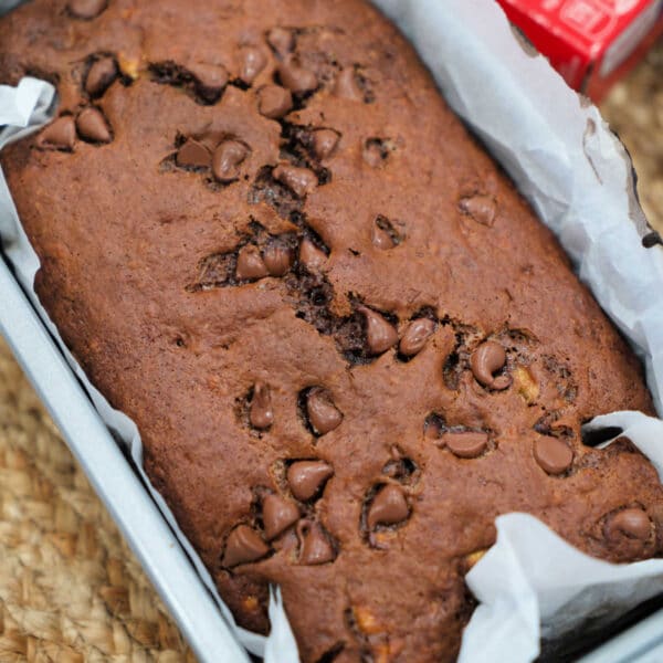 Chocolate banana bread in a parchment-lined loaf pan, fresh out of the oven.
