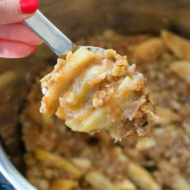 A spoon scoops out warm instant pot apple crisp, revealing tender apples and a golden oat topping.