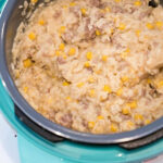 Creamy rice, ground beef, and corn mixture being stirred in a blue rice cooker—a delicious take on instant pot hamburger casserole.
