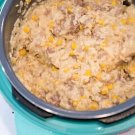 Creamy rice, ground beef, and corn mixture being stirred in a blue rice cooker—a delicious take on instant pot hamburger casserole.