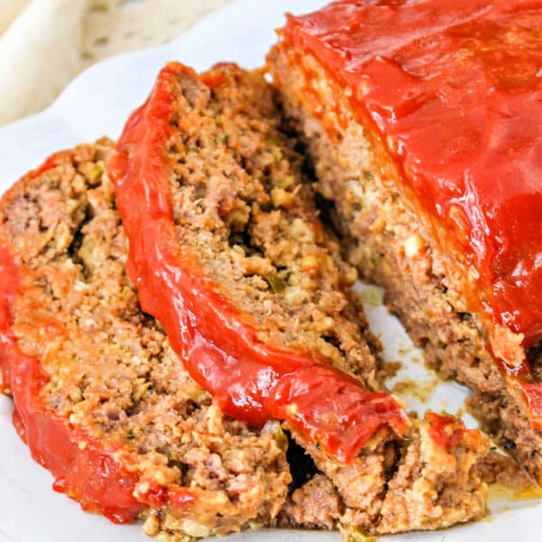 Sliced meatloaf topped with a glossy red ketchup glaze on a white plate—perfect for anyone craving a quick meatloaf recipe.