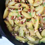Sautéed apple slices with chopped pecans and fresh herbs in a black skillet—perfect as a topping for your favorite baked pork chops recipe or to serve alongside pork chops with apples.