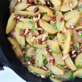 Sautéed apple slices with chopped pecans and fresh herbs in a black skillet—perfect as a topping for your favorite baked pork chops recipe or to serve alongside pork chops with apples.