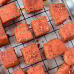 Seasoned, baked tofu cubes on a wire rack over parchment paper, inspired by BBQ burnt ends, ready to be served.