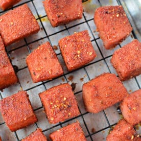 Seasoned, baked tofu cubes on a wire rack over parchment paper, inspired by BBQ burnt ends, ready to be served.
