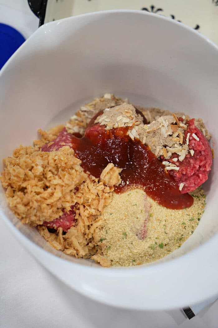 Unmixed meatloaf ingredients in a bowl, including ground beef, breadcrumbs, crushed chips, and sauce&mdash;perfect for starting your favorite BBQ meatloaf recipe.