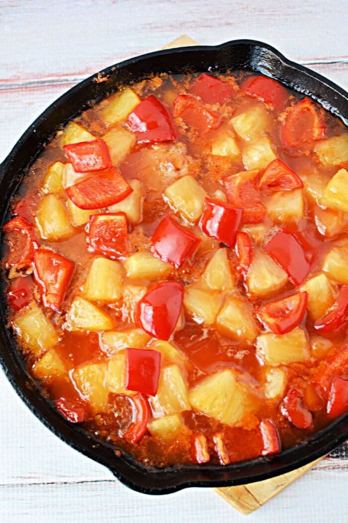 A skillet filled with sweet and sour sauce, pineapple chunks, red bell peppers, and tender pork chops—perfect for trying new pork chop recipes.