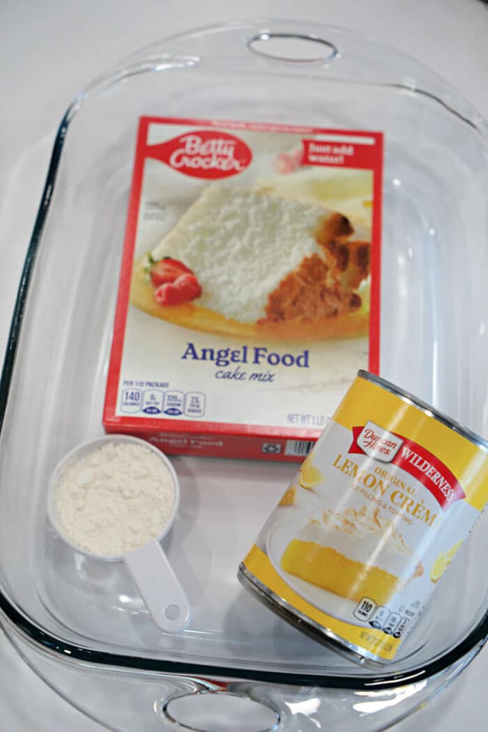 A glass baking dish with angel food cake mix, lemon creme pie filling, and a measuring cup of flour—perfect for preparing dessert after trying a new Carnivore Meatloaf or your favorite meatloaf recipe.