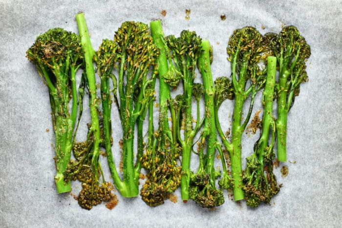 Oven roasted broccolini arranged on parchment paper, perfectly lightly browned and seasoned for a flavorful bite.