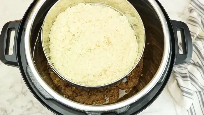 Overhead view of rice in a bowl stacked over instant pot Korean beef on a marble surface.
