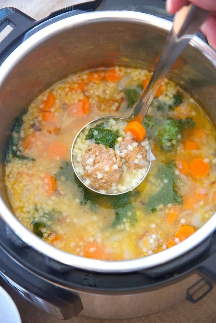 A ladle lifts meatball and vegetable soup from an Instant Pot, showing carrots, greens, and pasta&mdash;perfect inspiration for instant pot soup recipes.